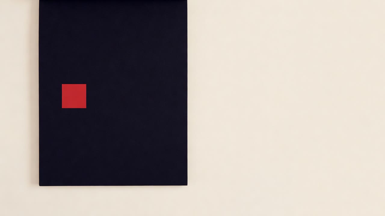 A black paper pad with one small red square, on a cream surface